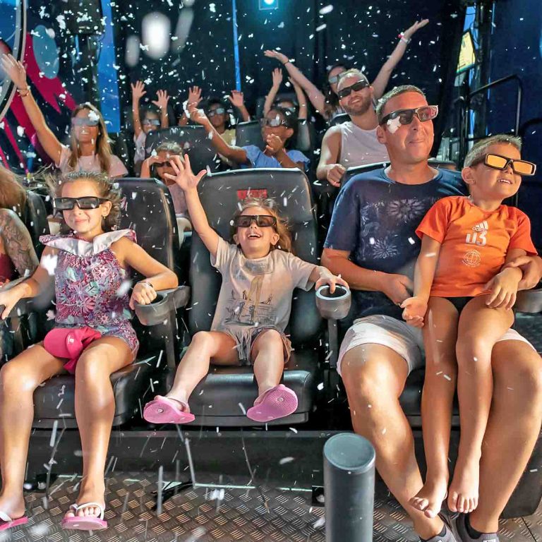 People wearing 3D glasses enjoying an indoor simulation ride with snow effects.