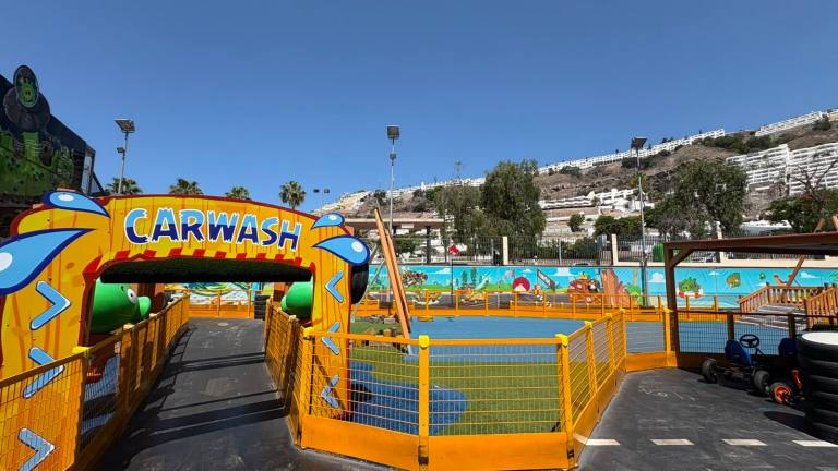 Colorful children's carwash-themed play area with slides and fences under a clear sky.