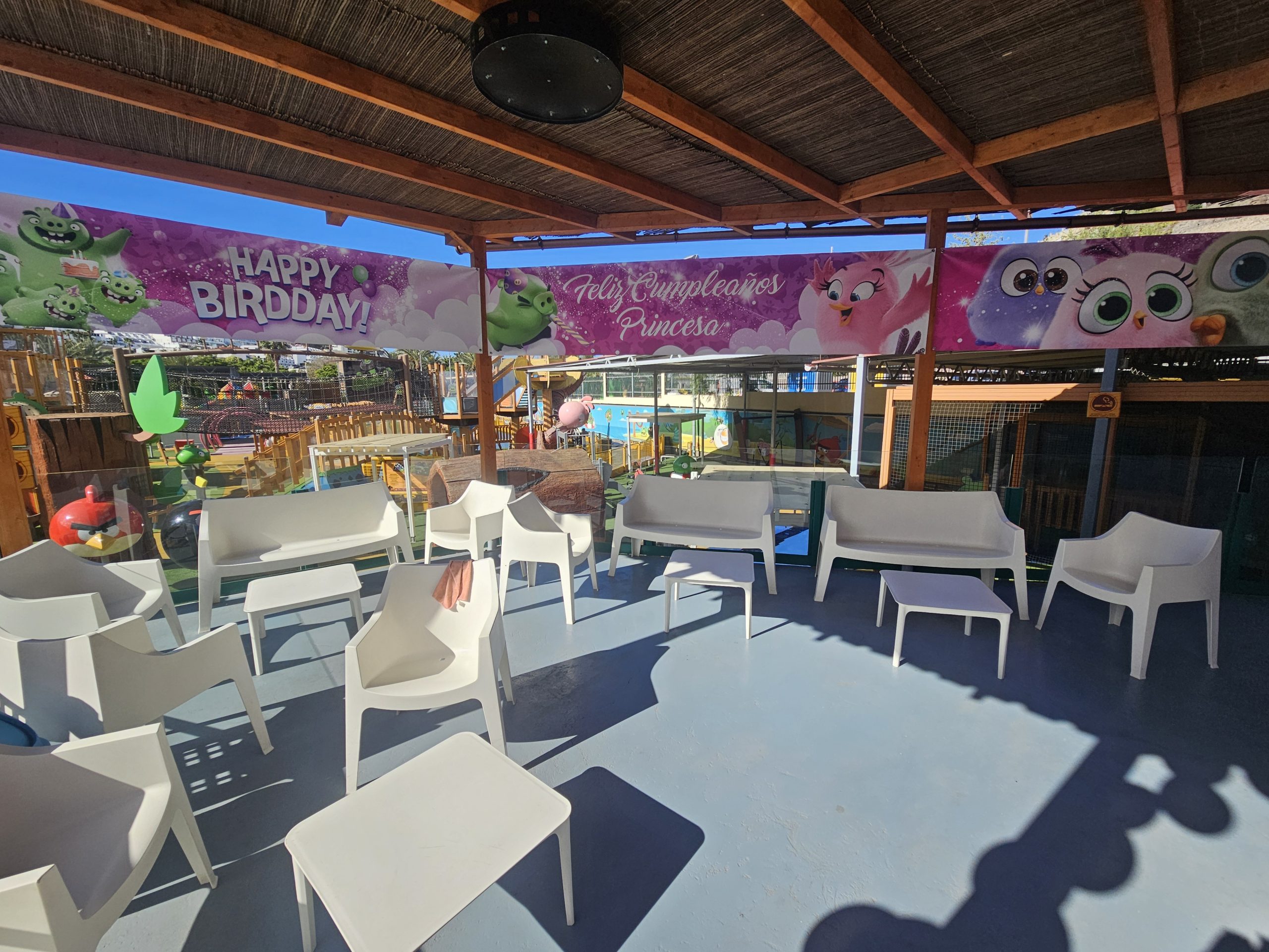 Outdoor birthday decor with white chairs, cartoon banner overhead.