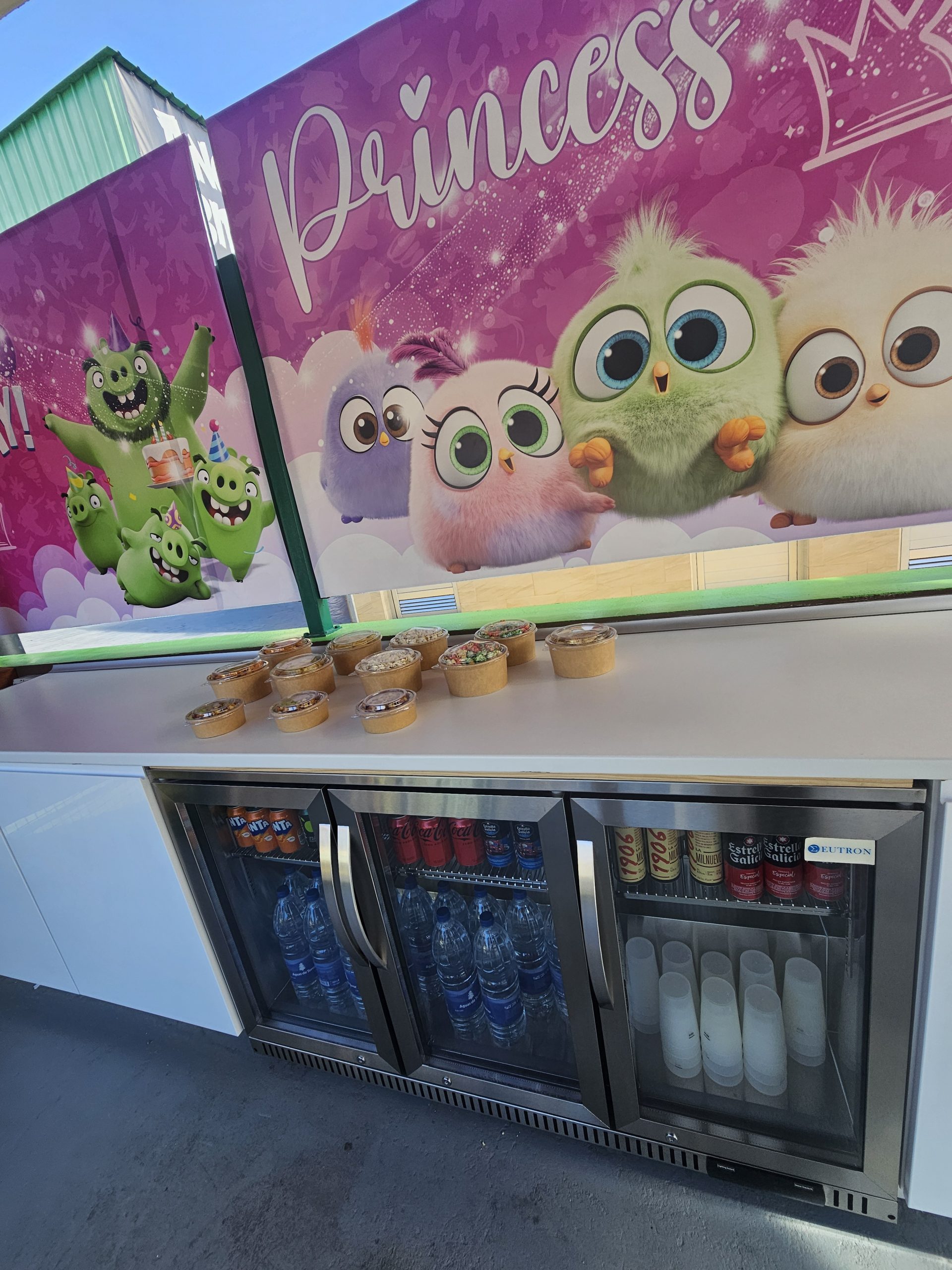 Snack display with colorful cartoon birds and beverages in a cooler below.
