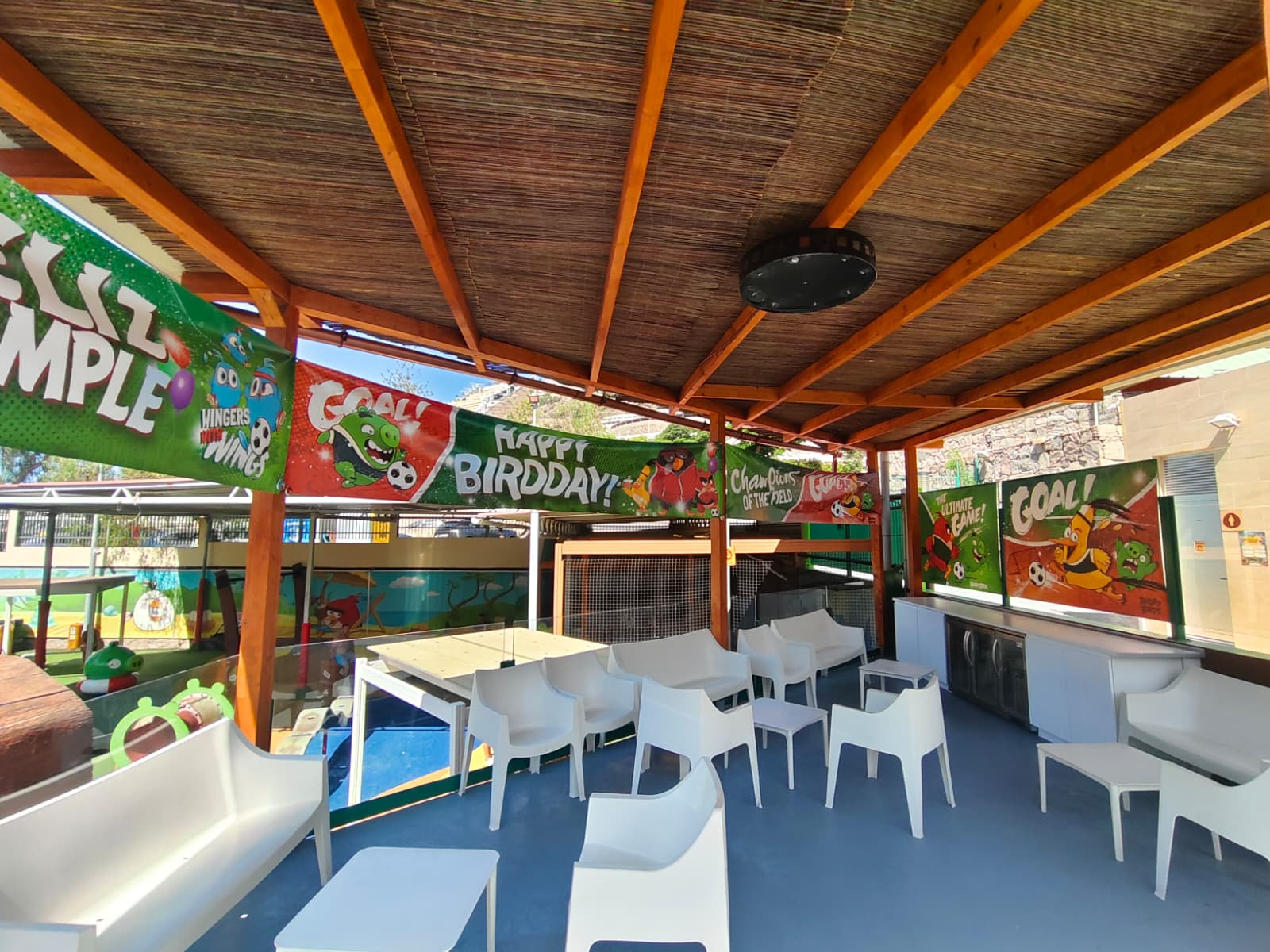 Covered outdoor area with colorful birthday banners and white chairs.
