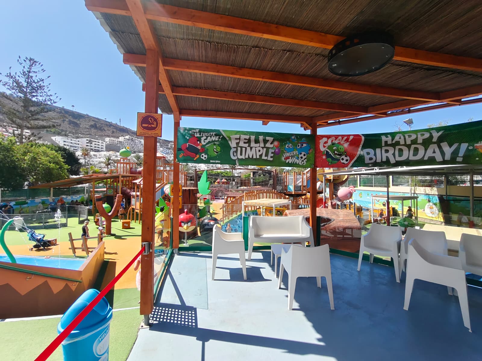 Outdoor children's play area with birthday decorations and seating under a pergola.