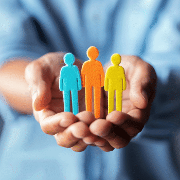 Hands holding three colorful paper cutout figures of people.